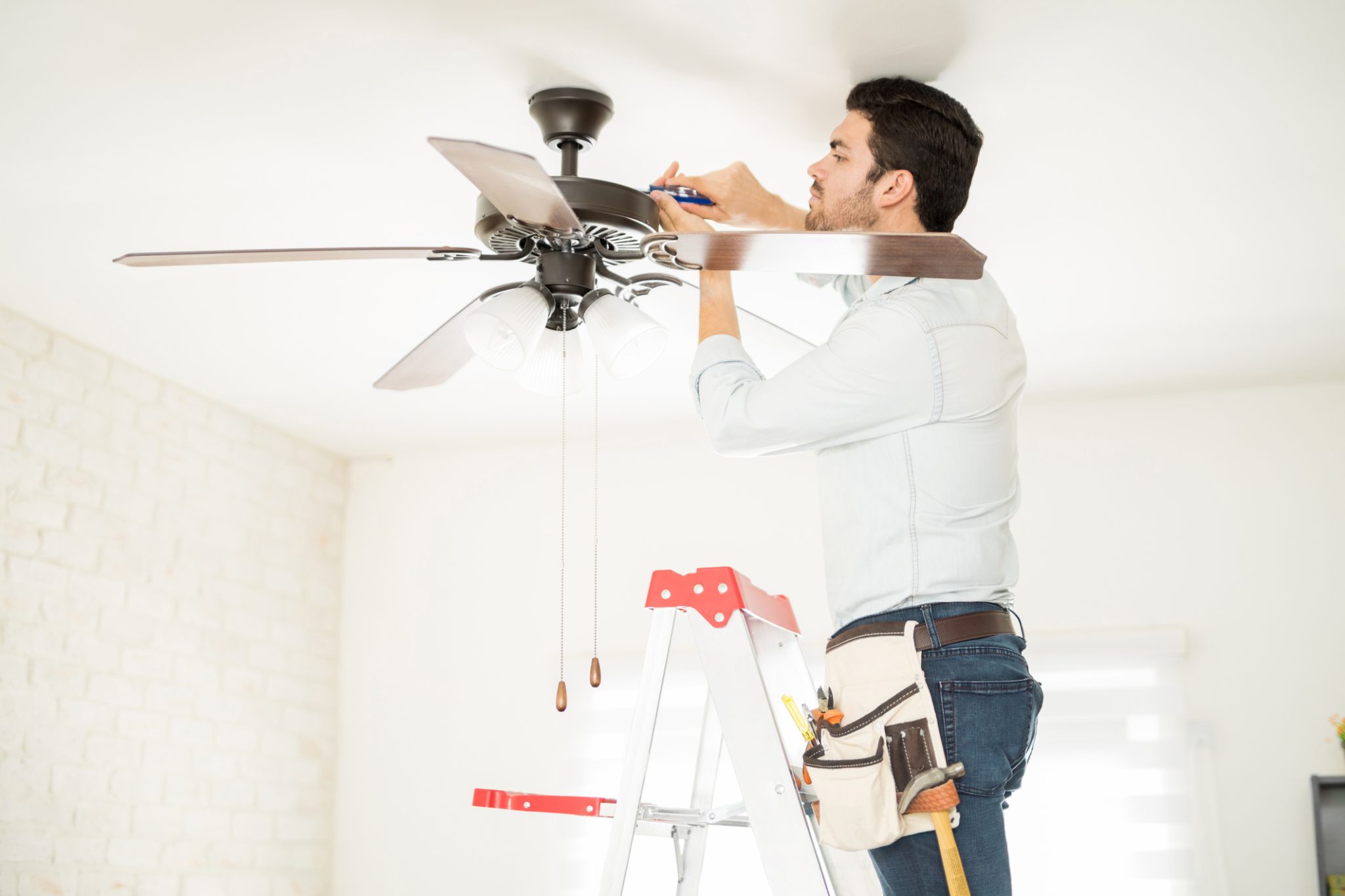 Electrician installing energy-efficient fan in Arizona home to help keep the space cool and lower energy bills.