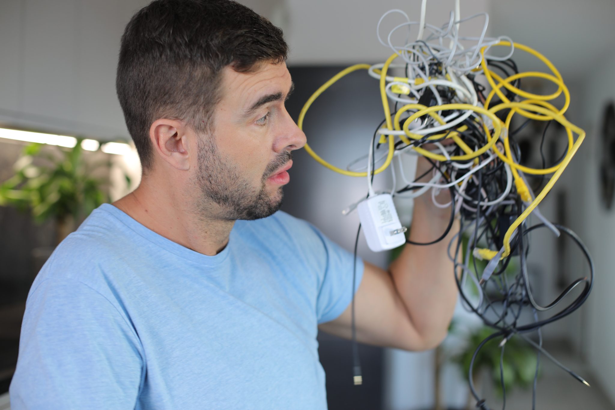 Frustrated man holding wires while trying to figure out if he needs an electrician for EV charger installation.